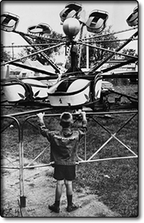 Boy in buckskin jacket watches rides on the Midway